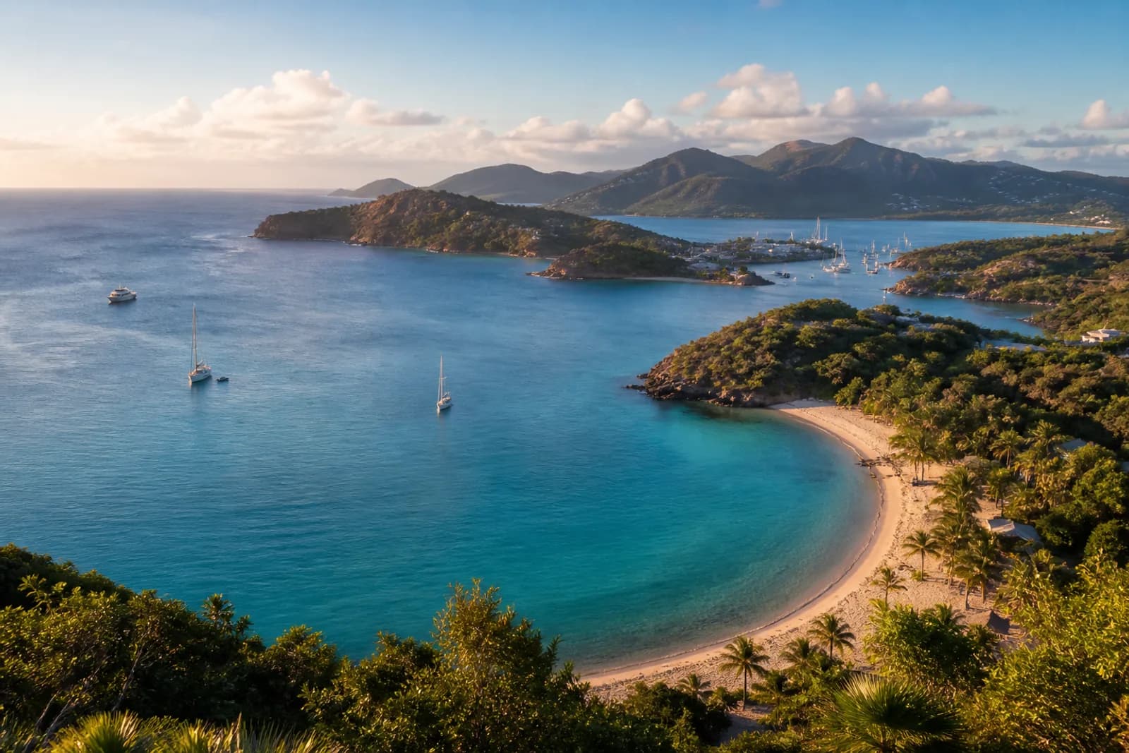 Antigua coastline with a sheltered turquoise bay, palms, and distant sailboats