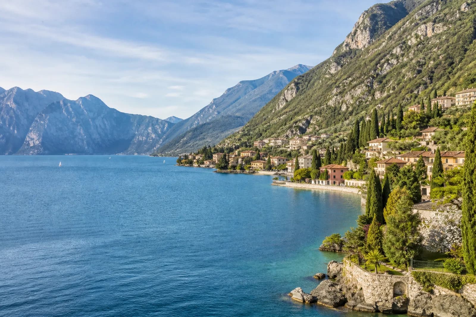 Lake Garda villages and cypress trees below steep green mountains