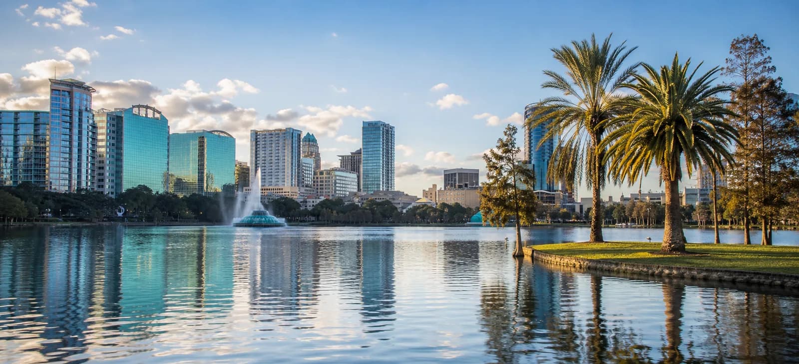 Orlando skyline and Lake Eola framed by palm trees in warm light