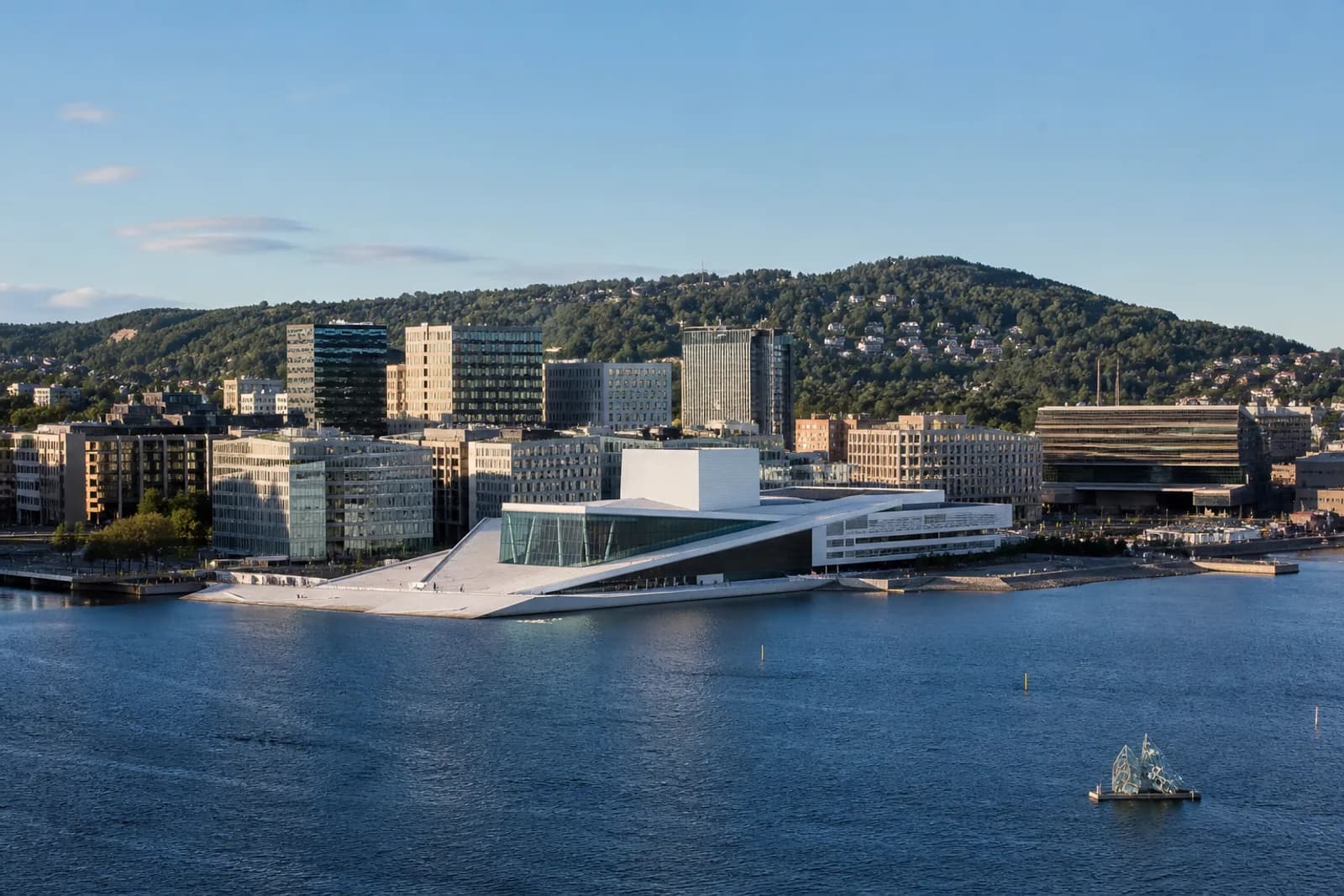 Oslo Opera House and harbour waterfront with green hills above the fjord