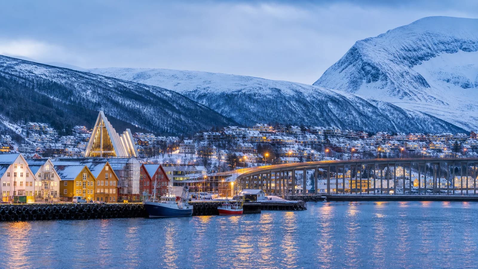 Tromsø harbour and Arctic Cathedral below snowy mountains beside the fjord